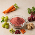 Nature Delights ABCG powder (amla, beetroot, carrot and ginger) in a glass bowl with fresh carrots, amla, beetroot and ginger