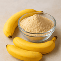 Nature Delights banana powder in a glass bowl with ripe bananas